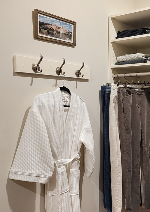 Custom Small Walk-In Closet with Designer Organization Details with a Robe Hook Rack and Open Shelving